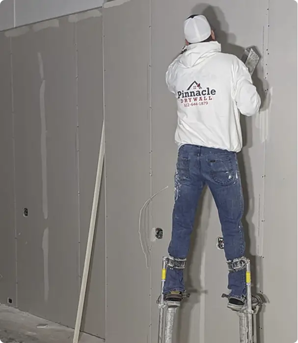 Worker finishing drywall on interior wall