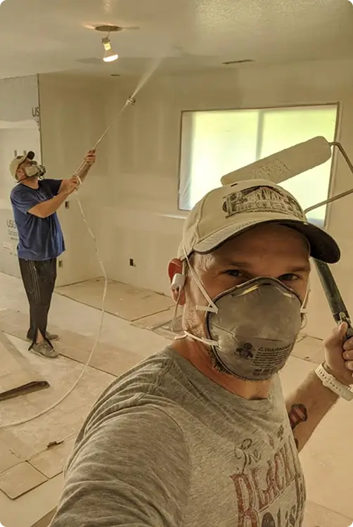 Drywall workers spraying and finishing interior walls during residential renovation project